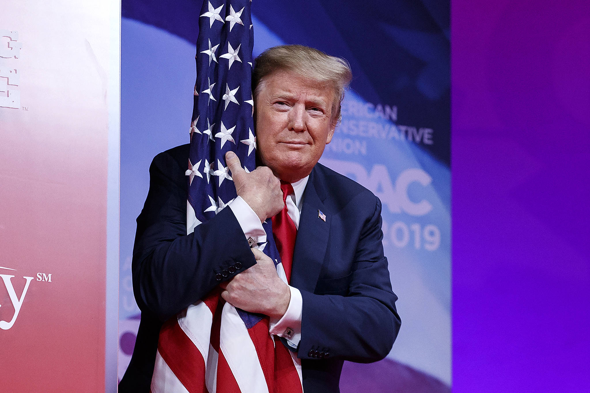 President Donald Trump hugs the American flag as he arrives to speak at Conservative Political Action Conference, CPAC 2019, in Oxon Hill, Md., Saturday, March 2, 2019. (AP Photo/Carolyn Kaster)