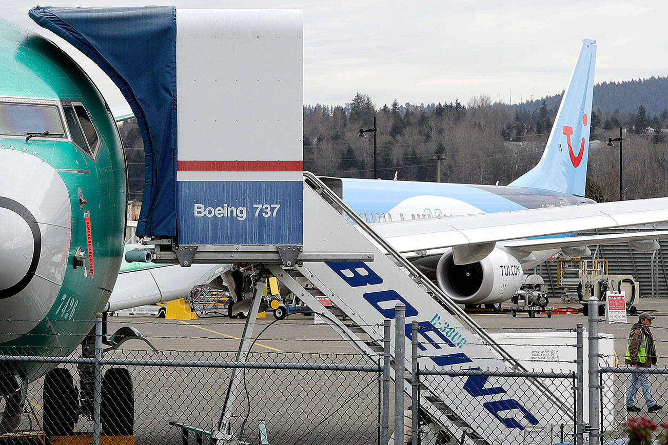 In this photo taken Monday, March 11, 2019, a Boeing 737 MAX 8 airplane being built for TUI Group sits parked in the background at right at Boeing Co.’s Renton Assembly Plant in Renton, Wash. Britain, France and Germany on Tuesday joined a rapidly growing number of countries grounding the new Boeing plane involved in the Ethiopian Airlines disaster or turning it back from their airspace, while investigators in Ethiopia looked for parallels with a similar crash just five months ago. (AP Photo/Ted S. Warren)