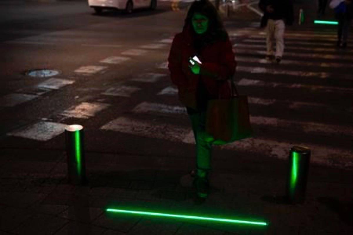 In this Wednesday, March 13, 2019 photo, An Israeli woman walks past embedded LED stoplights at a crosswalk in Tel Aviv, Israel. Tel Aviv has taken its first steps to assist pedestrians distracted by their smartphones by embedding LED stoplights at crosswalks. (AP Photo/Sebastian Scheiner)