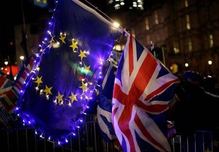 Anti-Brexit supporters hold an EU and British union flag outside the Houses of Parliament in London, Wednesday, March 13, 2019. (AP Photo/Tim Ireland)