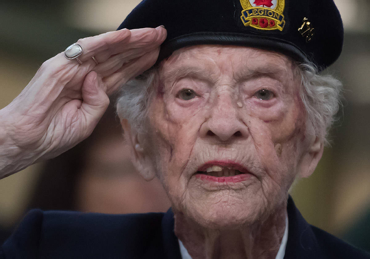 Agnes Keegan, who served in the British Army during the Second World War and now lives in Canada, salutes while singing the national anthem during a departure ceremony for a pair of combat boots that will travel to Halifax on a VIA Rail train, at Pacific Central Station in Vancouver, on Friday March 29, 2019. The boots will travel across the country on the train to symbolize those who travelled to Halifax during the Second World War before they embarked for Europe. The journey is part of the federal government’s plan to commemorate the 7th anniversary of D-Day and the Battle of Normandy. (Darryl Dyck/The Canadian Press)